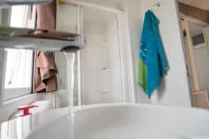 uma casa de banho com um lavatório e uma toalha azul na parede em Adria Holiday Villaggio San Francesco em Duna Verde