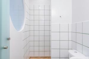 アテネにあるCabins Sleepingの白いタイル張りのバスルーム(トイレ、シャワー付)