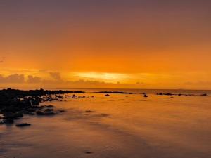 zachód słońca na plaży z kamieniami w wodzie w obiekcie Nautilus Right on the Beach - Adult Only - SHA Extra Plus w mieście Ko Lanta