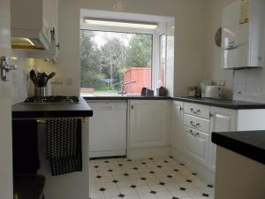 a kitchen with white cabinets and a sink and a window at BOURNECOAST: LOVELY BUNGALOW NEAR THE SEA - HB2087 in Bournemouth
