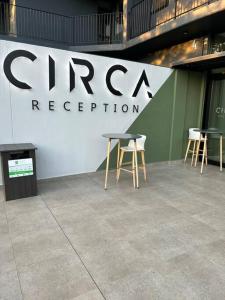 a group of tables and chairs in front of a sign at Circa Apartment 86 in Pretoria