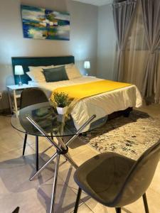 a bedroom with a bed and a glass table and chairs at Circa Apartment 86 in Pretoria