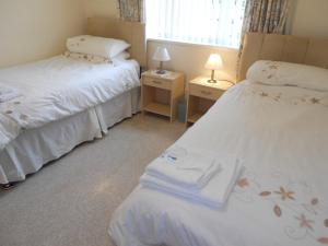a bedroom with two beds and two lamps and a window at BOURNECOAST: LOVELY BUNGALOW NEAR THE SEA - HB2087 in Bournemouth +38 photos