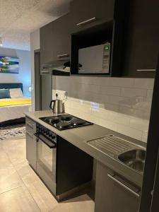 a kitchen with a stove and a sink and a bed at Circa Apartment 86 in Pretoria