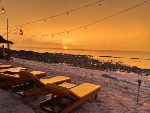 eine Gruppe von Tischen und Stühlen am Strand bei Sonnenuntergang in der Unterkunft Nautilus Right on the Beach - Adult Only - SHA Extra Plus in Ko Lanta