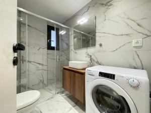 La salle de bains est pourvue d'une douche et d'un lave-linge. dans l'établissement Gleaming apartments near Athens Metro Mall, à Athènes