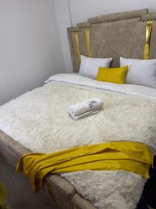 a bed with a yellow and white blanket on it at Serene 2 Bedrooms Apartment in Kericho