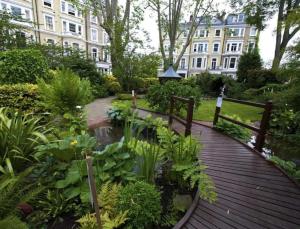 a wooden walkway in a garden in front of a building at Stunning 2 bed/2bath flat in heart of Kensington in London