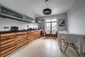 a kitchen with wooden cabinets and a table and chairs at Park Szczytnicki Cosy Apartment in Wrocław