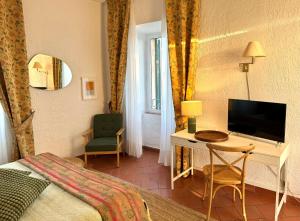 ノーヴィ・リーグレにあるAgriturismo Tenuta la Marchesaのベッド、デスク、テレビが備わるホテルルームです。
