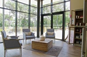 a living room with chairs and a table and windows at Domaine du Ferret Restaurant & Spa in Cap-Ferret
