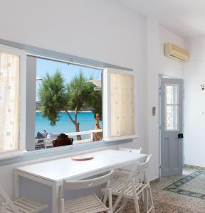 a white dining room with a window with a view of the beach at Grandma's sifnos house in Platis Gialos