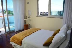 a bedroom with a large bed with two windows at Moradia Vista Atlântico in Funchal