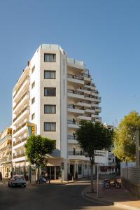 ein hohes weißes Gebäude mit einer Straße davor in der Unterkunft Hotel Orosol in Sant Antoni de Portmany