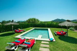 a swimming pool with lawn chairs and umbrellas at Villa Figueral by Villa Plus in Alcudia
