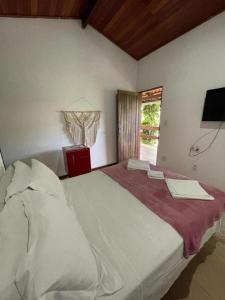 a bedroom with a large white bed with a window at Chez Max Pousada in Morro de São Paulo