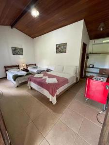 a bedroom with two beds and a red table at Chez Max Pousada in Morro de São Paulo