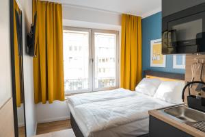 een slaapkamer met een bed en een raam met gele gordijnen bij Antares Apartments in Düsseldorf