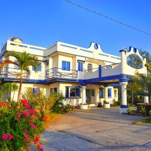 un gran edificio blanco con una palmera delante en Club Monet Beachfront Resort by Cocotel, en Zambales