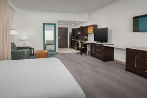 Habitación de hotel con cama y escritorio con TV. en Home2 Suites Orlando Southeast Nona en Orlando