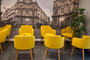 a waiting room with yellow chairs and a painting of buildings at Alma Hotel in Palermo