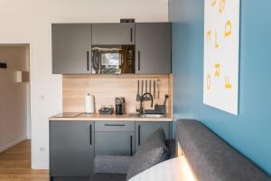 デュッセルドルフにあるAntares Apartmentsのキッチン(グレーのキャビネット、カウンタートップ付)