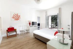 een witte slaapkamer met een bed, een tafel en een raam bij AMORE RENTALS - Appartamento Carmela in Sorrento