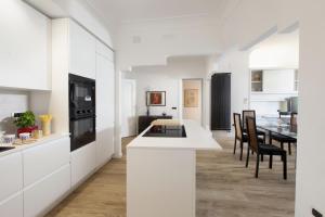 ソレントにあるAMORE RENTALS - Appartamento Carmelaの白いキャビネット、テーブルと椅子付きのキッチンが備わります。