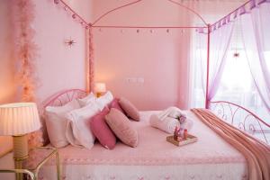 een roze bed met roze kussens en een baldakijn bij Esclusiva Villa Romantica con Sauna & Piscina Privata a 10 minuti dall arena di Verona Il Rifugio Perfetto per una Fuga d'Amore in Verona