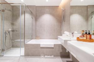 een badkamer met 2 wastafels en een douche bij Manzil - 3BR + Maid in District One with Burj View in Dubai