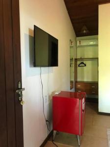 Chez Max Pousada في مورو دي ساو باولو: تلفزيون بشاشة مسطحة على جدار مع خزانة حمراء