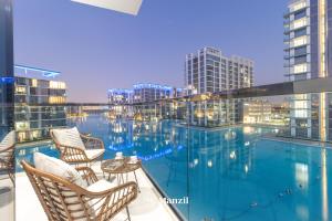 een balkon met stoelen en een zwembad bij Manzil - 3BR + Maid in District One with Burj View in Dubai