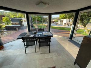 eine abgeschirmte Veranda mit einem Tisch und Stühlen in der Unterkunft Le p'tit clos de Choz (1 ou 2 chambres) in Chozeau