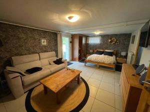 ein Wohnzimmer mit einer Couch und einem Bett in der Unterkunft Le p'tit clos de Choz (1 ou 2 chambres) in Chozeau