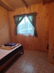 um quarto com uma cama e uma janela em cabaña zoila em Coñaripe