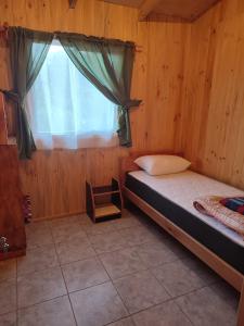 um pequeno quarto com uma cama e uma janela em cabaña zoila em Coñaripe