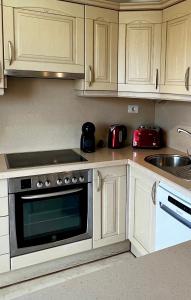 a kitchen with white cabinets and a stove top oven at Elegant Palm Mar Apartment in Palm-Mar