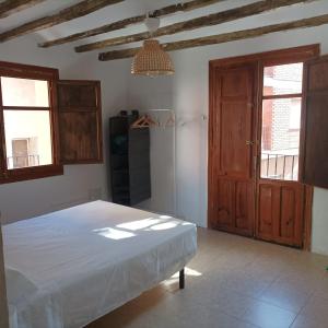 Schlafzimmer mit einem Bett und einer Holztür in der Unterkunft El Albergue Cirat in Cirat
