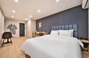a bedroom with a large white bed with a blue wall at Hotel Daon in Pohang