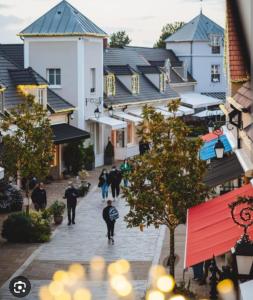 eine Gruppe von Menschen, die eine Straße mit Gebäuden entlanggehen in der Unterkunft Magnifique appartement proche de Paris et de Disney in Lognes