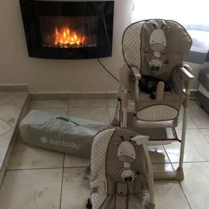 a childs car seat and a bed next to a fireplace at Flóra vendégház Tiszafüred in Tiszafüred