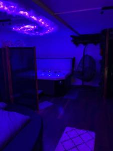 ciemny pokój z fioletowymi światłami i łóżkiem w obiekcie Le 36/Espace bien-être privatif w mieście Bellevaux