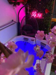 een kamer met paarse verlichting en bloemen en een klok bij Le 36/Espace bien-être privatif in Bellevaux