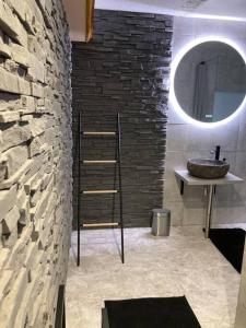 a bathroom with a sink and a stone wall at Le 36/Espace bien-être privatif in Bellevaux