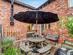 a wooden picnic table with an umbrella and benches at 4 Bed in Shrewsbury 50180 in Pontesbury