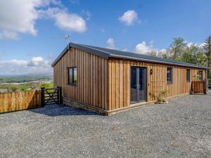 a wooden cabin with a fence in a gravel lot at 2 Bed in Bentham 53510 in High Bentham