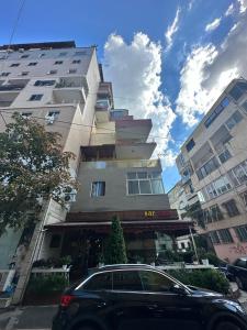 un'auto parcheggiata di fronte a un edificio alto di Sunshine Apartment Tirana, Sheshi Wilson a Tirana