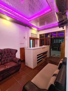 ein Wohnzimmer mit Sofa und lila Beleuchtung in der Unterkunft Penginapan Nurmega jaya 