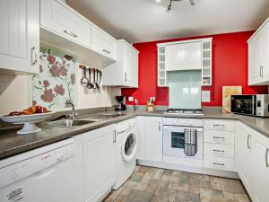 een keuken met witte kasten en rode muren bij 3 bed in Eastbourne EHC26 in Eastbourne