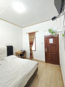 a bedroom with a bed and a wooden door at Penginapan Nurmega jaya 